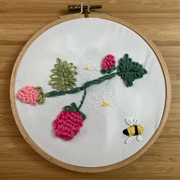 Embroidery combining code-stitched flowers and a hand-stitched bee.