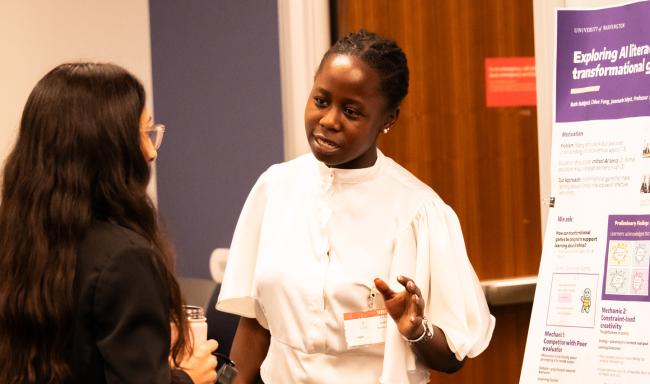 Informatics student Ruth Nakigozi speaks to a woman in front of her poster.