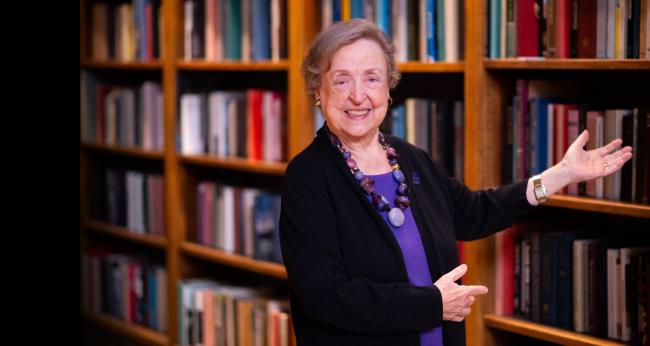 Marcie Stone gestures toward a bookshelf.