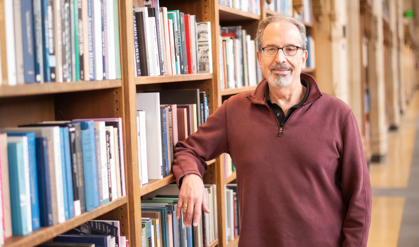 David Levy stands among the bookshelves at Suzzallo Library.