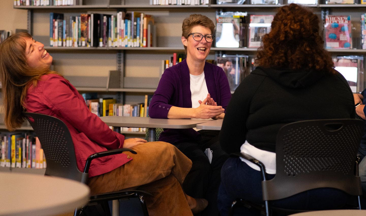 Helene Williams laughs while speaking with three alumni.