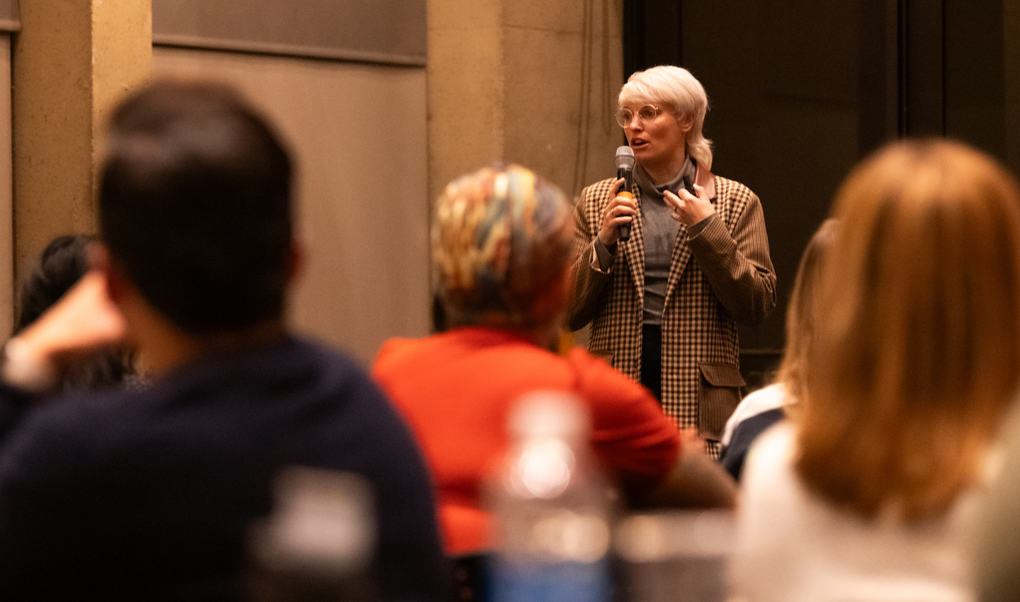 Emily Witko speaks in front of a seated crowd.