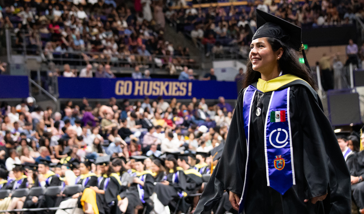A graduate smiles as she approaches the stage to receive her degree.