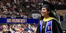 A graduate smiles as she approaches the stage to receive her degree.