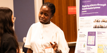 Informatics student Ruth Nakigozi speaks to a woman in front of her poster.
