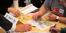 Hands work through parts of an escape-room puzzle.
