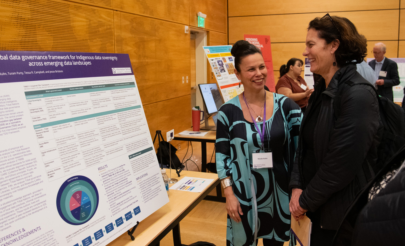 Two women share a laugh among research posters.