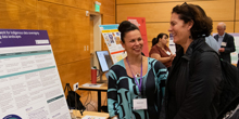 Two women share a laugh among research posters.