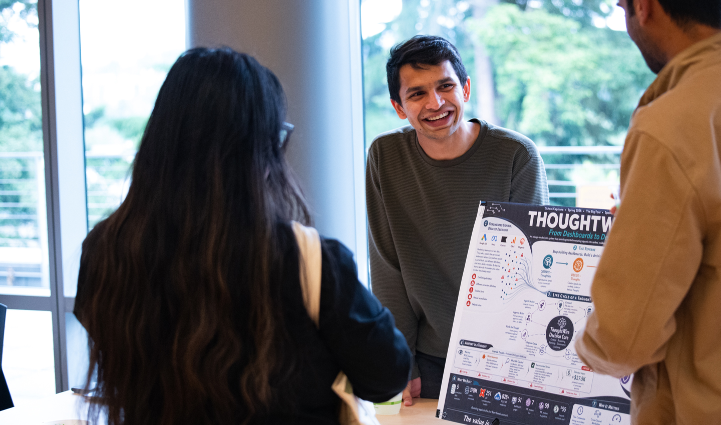 A man discusses his project poster with visitors.
