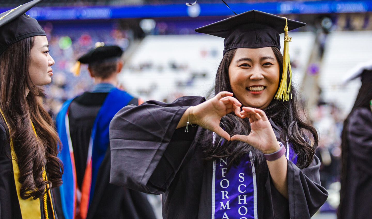 A woman makes a heart gesture at Commencement.