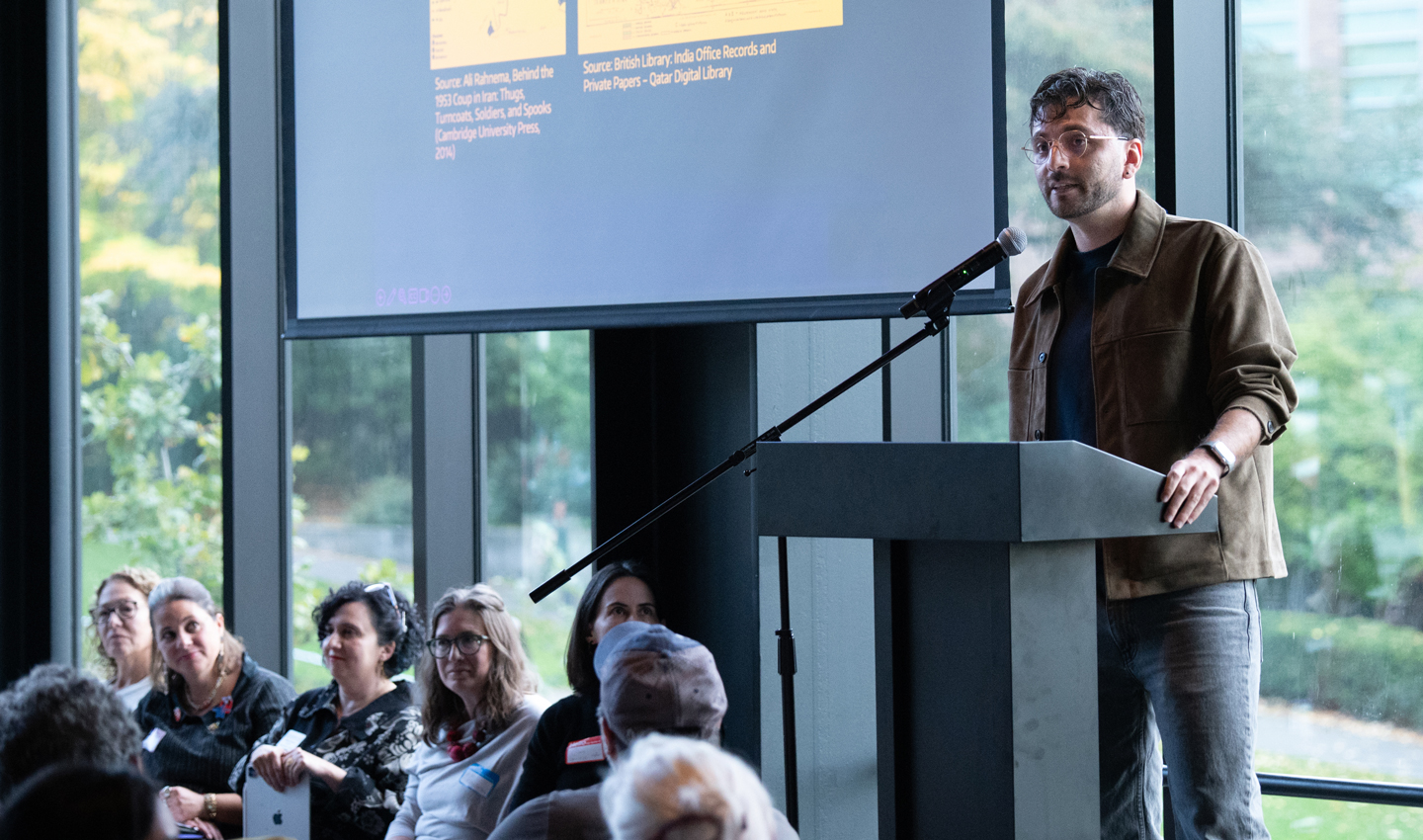Mert Can Bayar presents at a podium in front of a screen.