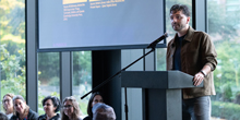 Mert Can Bayar presents at a podium in front of a screen.
