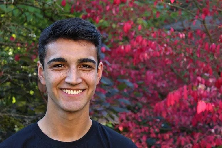 Sam Martinez pictured in front of bright red foliage in a senior portrait.