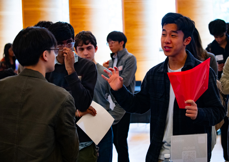 A young man gestures while speaking to a company representative.