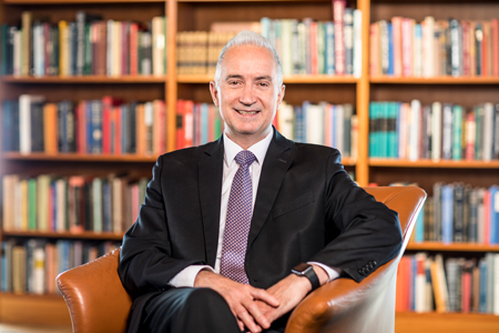 Harry Bruce, seated in front of a large bookshelf.