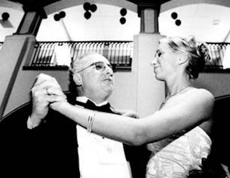 Mike Eisenberg dances with a woman while wearing a tuxedo.