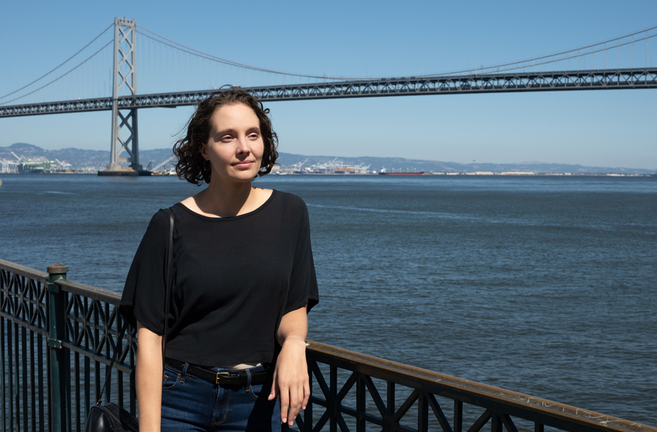 Gennie Gebhart looks out over the water with the San Francisco Bay Bridge in the background.