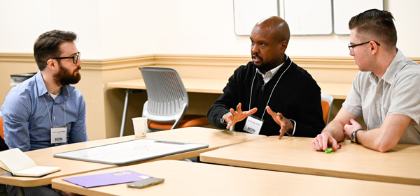 Three men in a discussion in a classroom