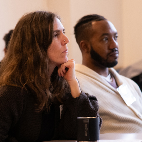 A woman and man listen intently in a classroom