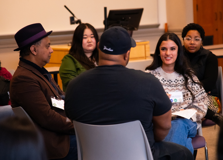 A woman speaks with a man while surrounded by other attendees.