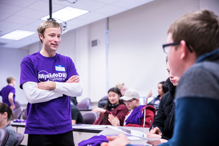 Associate Professor Jevin West speaks to teens while wearing a "MisinfoDay" t-shirt.