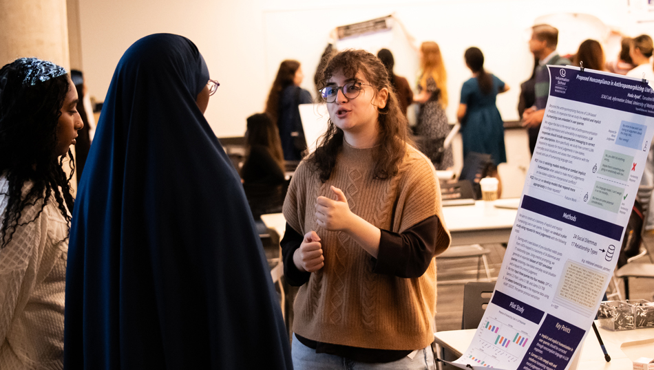 Informatics student Hoda Ayad speaks with two visitors about her poster.