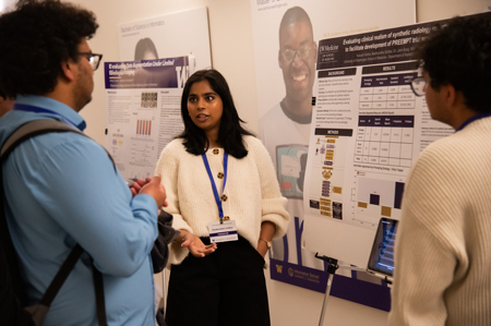 Madhumitha Sridhar speaks to a visitor in front of a research poster.