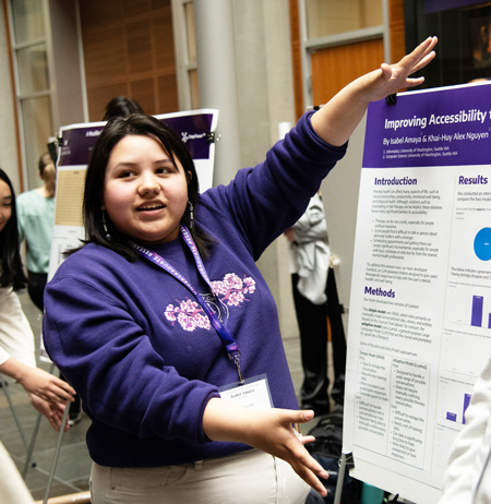 A student gestures as she presents a poster.