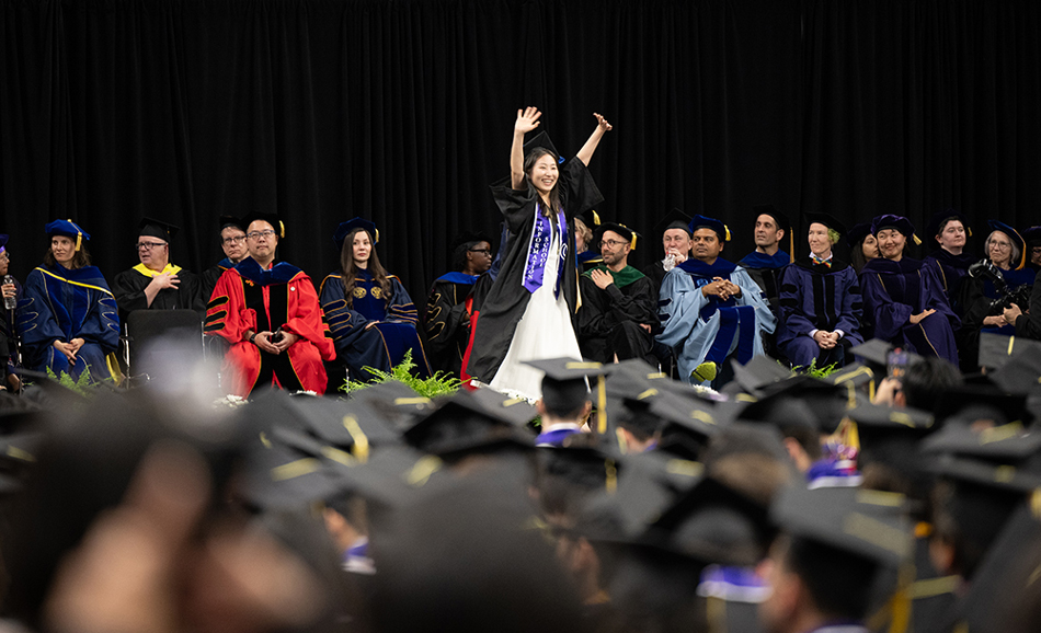 A graduate waves from the stage