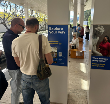 Two men look at a poster that reads "Explore your way" in a museum.