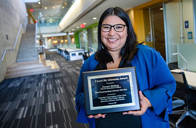 Naomi Bishop holds a plaque for her "I Love My Librarian" award.