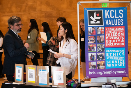 A student visits a KCLS library system table at the iSchool Career Fair.