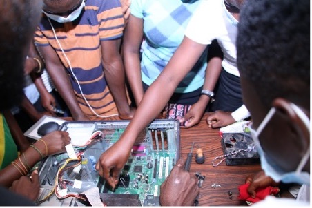 Young people's hands work with a computer motherboard.
