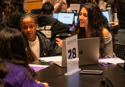 A student mentor speaks with kids at the Hack for Social Good hackathon
