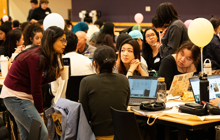 Women work with a mentor at the Winfo Hackathon.