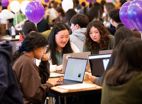 Two women collaborate in front of a computer screen.