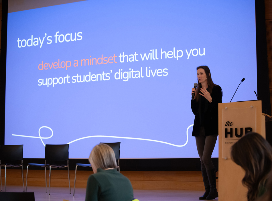 Katie Davis speaks on stage in front of a screen showing a slide that reads "Today's focus: Develop a mindset that will help you support students' digital lives."