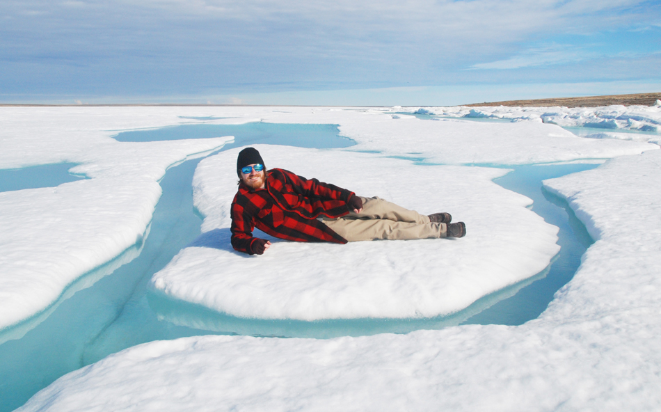 Jason Young lies in the ice outside Ulukhaktok, Canada.